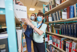 Библиотекари выбирают книги на полках