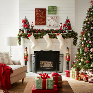 белый камин с гирляндой и вывешенными рождественскими чулками, слева кресло с красным пледом и белым торшером около него, справа украшенная елка с подарками