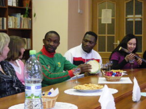 Молодые африканцы с национальными музыкальными инструментами и девушки за столом. Студенческий митап