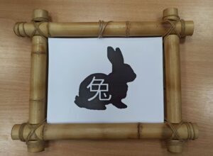 Иероглиф и черное изображение кролика в бамбуковой рамке
