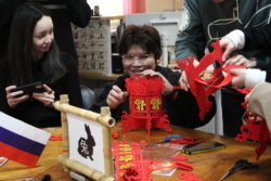 Китайский студент показывает, как собирать красный фонарик на мероприятии «Символы китайского календаря»
