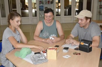 девочка, женщина и мужчина играют на столе в карты